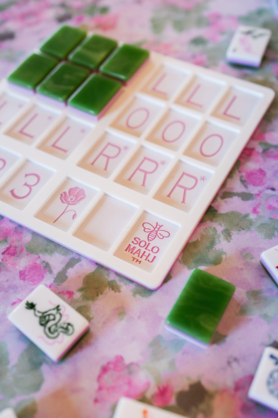 Close up of the SoloMahj Poppy practice board with green mahjong tiles on a pink floral surface