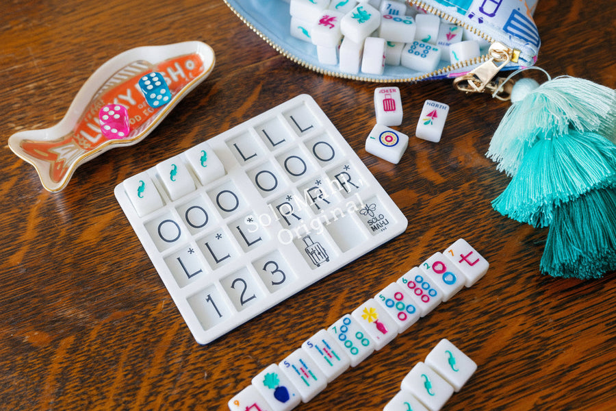 SoloMahj JetSetter board next to a fish-shaped dice dish and a travel pouch of mahjong tiles